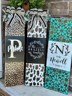 three wooden signs decorated with leopard print and monogrammed bows are sitting on the front porch