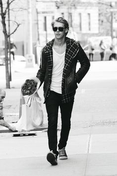 a man walking down the street with his hands in his pockets and wearing sunglasses on