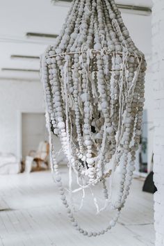 a chandelier made out of beads hanging from the ceiling in a white room