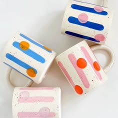 three coffee mugs with designs painted on them