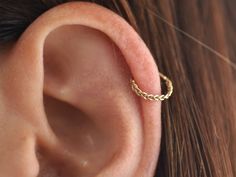 a woman's ear is shown with a gold chain in the shape of a ring