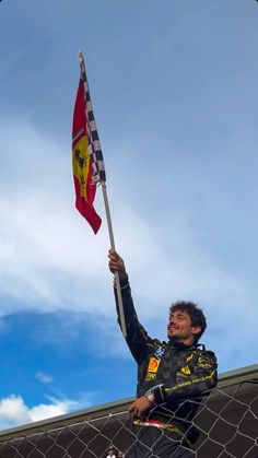 a man holding a flag on top of a fence