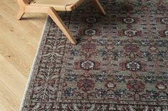 a wooden chair sitting next to a large rug on top of a hard wood floor