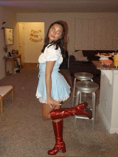 a woman in a short dress and red boots posing for the camera