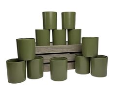 green cups are stacked on top of each other in front of a wooden stand that holds them