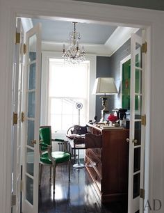 an open door leading to a living room with a desk and green chair in it