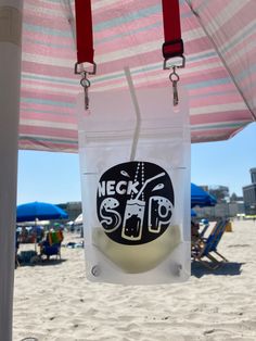 a bag hanging from the side of a beach umbrella with a logo on it and people in the background