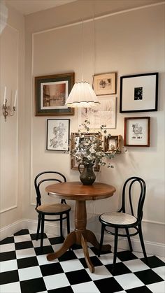 two chairs and a table in a room with pictures on the wall