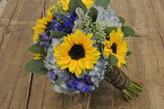 a bouquet of sunflowers and blue hydrangeas on a wooden table