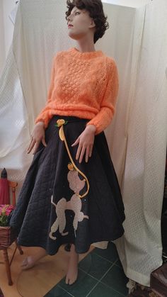 "This authentic 1950s Mid-Century Poodle Circle skirt could be the definitive addition to your vintage collection. Sporting the classic French cut is a 15 inch-high by 10 inch-wide beautiful Poodle Applique - set against a quilted black cotton background.  The Poodle's head, body, tail-end and cheek are fashioned from curly silver-grey wool.  The face, center body, feet and tail are a greige (grey/beige) colored felt. A cheerful yellow felt collar is set with three large rhinestones.   A yellow felt rose with two green leaves adorns the Poodle's head.  A yellow felt leash swirls up to the waistband -  festooned with a similar felt rose.  Around the Poodle is a sprinkling of 10 smaller rhinestones.  A Talon Zipper at the side is topped with three hook/eye closures. The birth of the iconic P 1950s Poodle Skirt, Poodle Applique, Festive Christmas Outfit, Felt Rose, Cotton Background, Rhinestone Collar, Vintage Mannequin, Felt Roses, Poodle Skirt