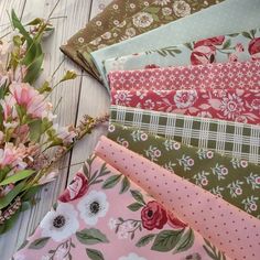 a bouquet of flowers sitting on top of a wooden table next to fabrics and fabric