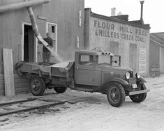 an old truck is parked in front of a building with pipes sticking out of it