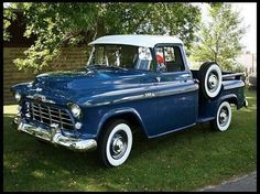 an old blue truck parked in the grass