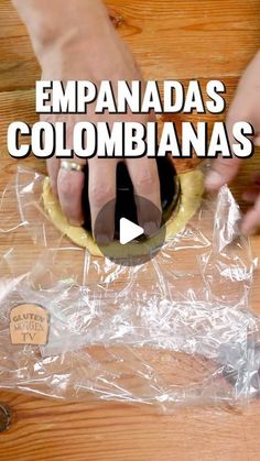 a person is making food on top of a wooden table with plastic wrap around it