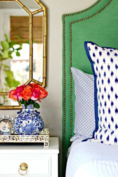 an image of a bed with pillows and flowers on it's headboard in front of a mirror