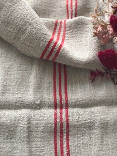 a red and white striped towel laying on top of a bed next to dried flowers