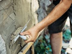 a man is working on a wall with cement