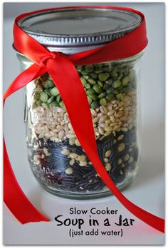 a jar filled with lots of food sitting on top of a white table next to a red ribbon