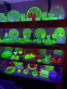 neon green dishes and plates are on display in a dark room with purple lighting behind them