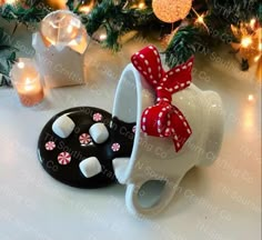 two coffee mugs decorated with bows and marshmallows are sitting on a table