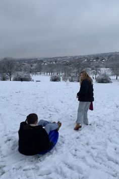 two people are playing in the snow on a sled