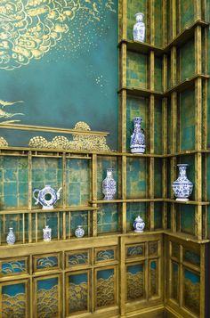 there are many blue and white vases on the shelves in this room, all lined up