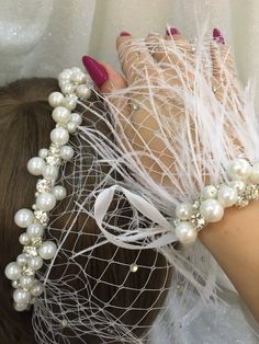 a close up of a person wearing a veil with pearls and feathers on their head