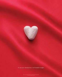 a white heart shaped pill laying on top of a red satin background with the word love written in it