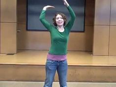 a woman standing in front of a tv holding her arms up to the side with both hands