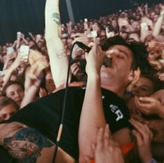 a man with his arms up in the air while holding a microphone at a concert