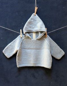 a knitted sweater hanging on a clothesline with two pegs attached to it