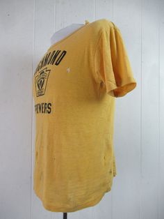 "Vintage 1960s yellow cotton t shirt with black graphics: Richmond Brewers Little League Baseball. Made by Southern Athletic. Size small. Actual measurements are: 38\" around the chest 38\" around the waist 17.5\" shoulder seam to shoulder seam 23\" overall length In \"wrecked\" condition with several holes." Vintage Fitted T-shirt With Letter Print, Retro Yellow T-shirt With Letter Print, Retro Yellow T-shirt With Graphic Print, Yellow Retro T-shirt With Graphic Print, Retro Yellow Short Sleeve T-shirt, Yellow Retro Short Sleeve T-shirt, Retro Yellow T-shirt With Screen Print, Vintage Cropped T-shirt For Summer, Fitted Vintage T-shirt With Screen Print