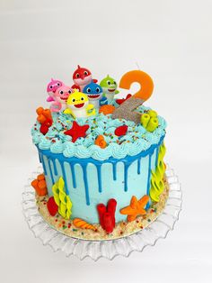 a birthday cake with blue icing and colorful decorations on it's bottom tier