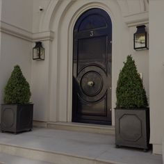 two black planters sitting in front of a door