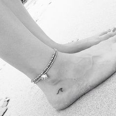 a woman's foot with a tattoo on it and a beaded bracelet around her ankles