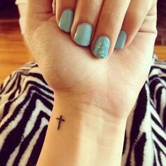 a woman's wrist with a cross tattoo on it