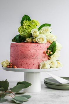 a pink cake with white flowers and greenery on top