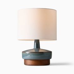 a lamp that is sitting on top of a wooden base with a white shade over it