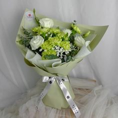 a bouquet of green and white flowers wrapped in ribbon