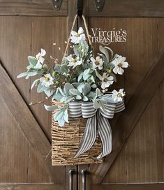 a wicker basket with flowers hanging from the side on a wooden door hanger