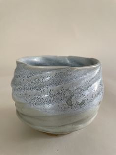 a close up of a white bowl on a table with a light colored surface in the background