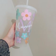 a person holding up a cup with flowers on it