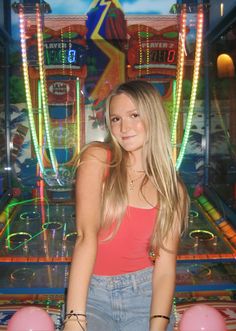 a young woman standing in front of a pinball machine with her hands on her hips