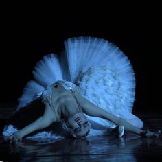 a woman in white dress laying on the ground with her arms around her body and head