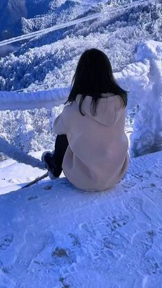 a woman sitting on top of a snow covered slope