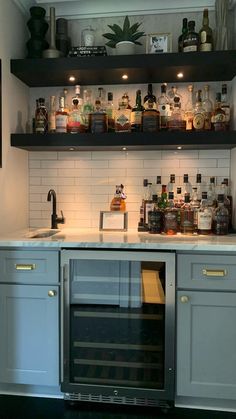 a kitchen filled with lots of bottles and glasses on top of the shelves above the sink