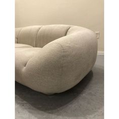 an oval shaped couch sitting on top of a cement floor next to a white wall