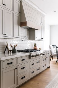 a kitchen with white cabinets and an oven in the center is featured by remeddy