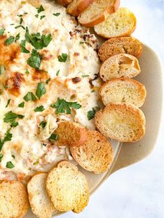 a white plate topped with cheese and crackers next to garlic bread on a table