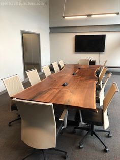 an empty conference room with chairs and a large wooden table in front of a flat screen tv